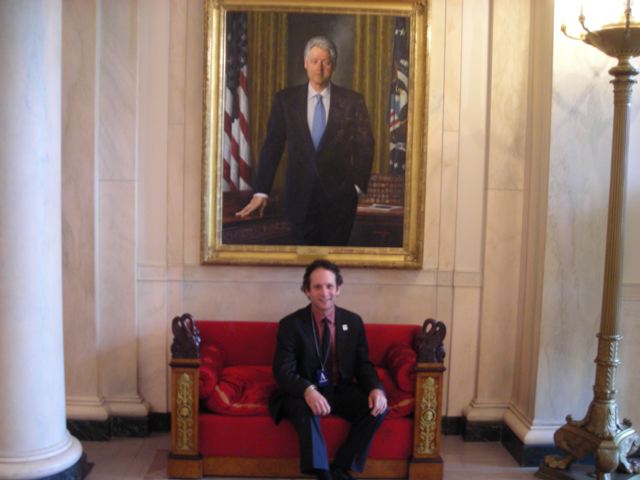 Eli Yamin under portrait of former President Clinton